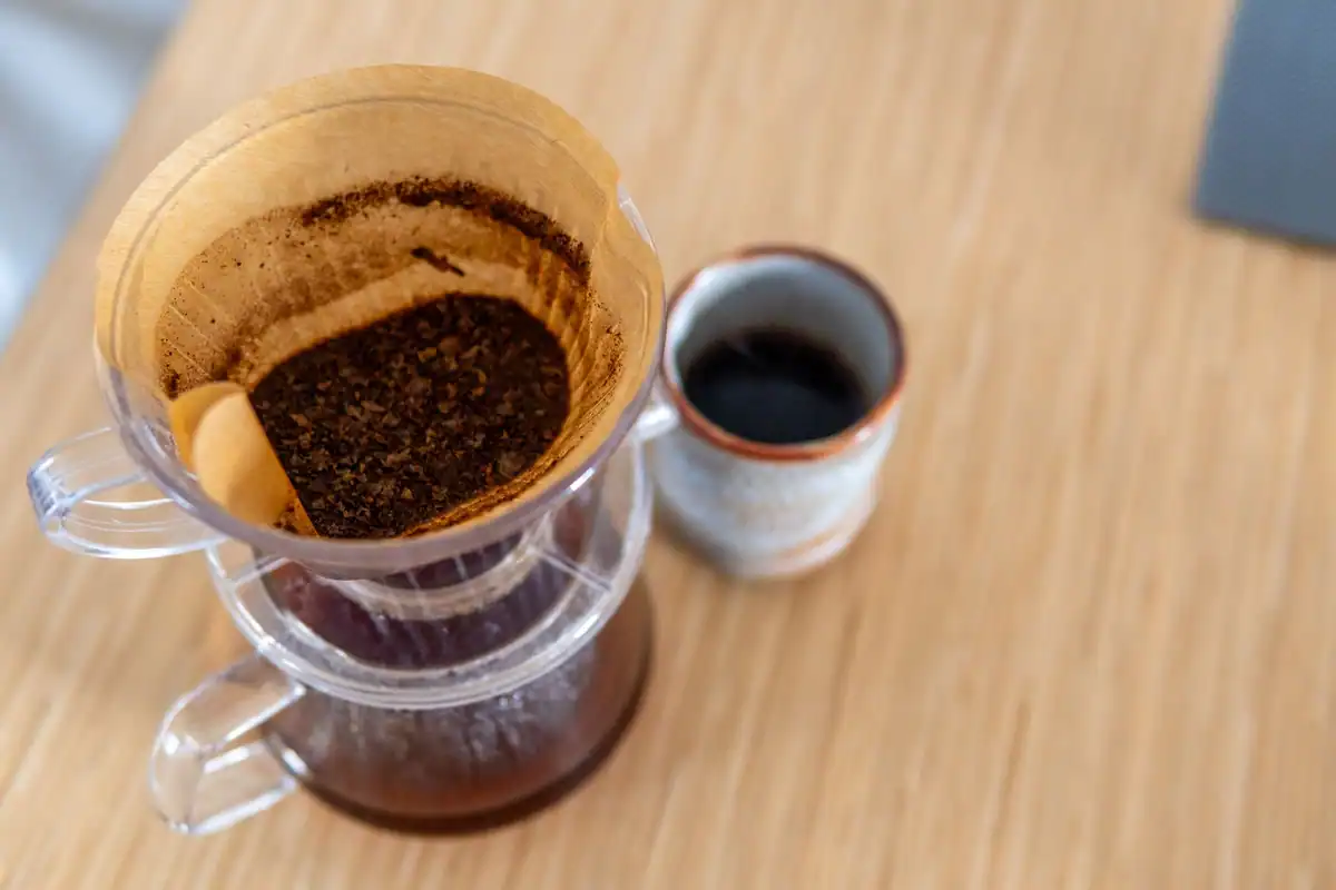 Cafea la filtru preparată lângă o cană de ceramică pe o masă din lemn