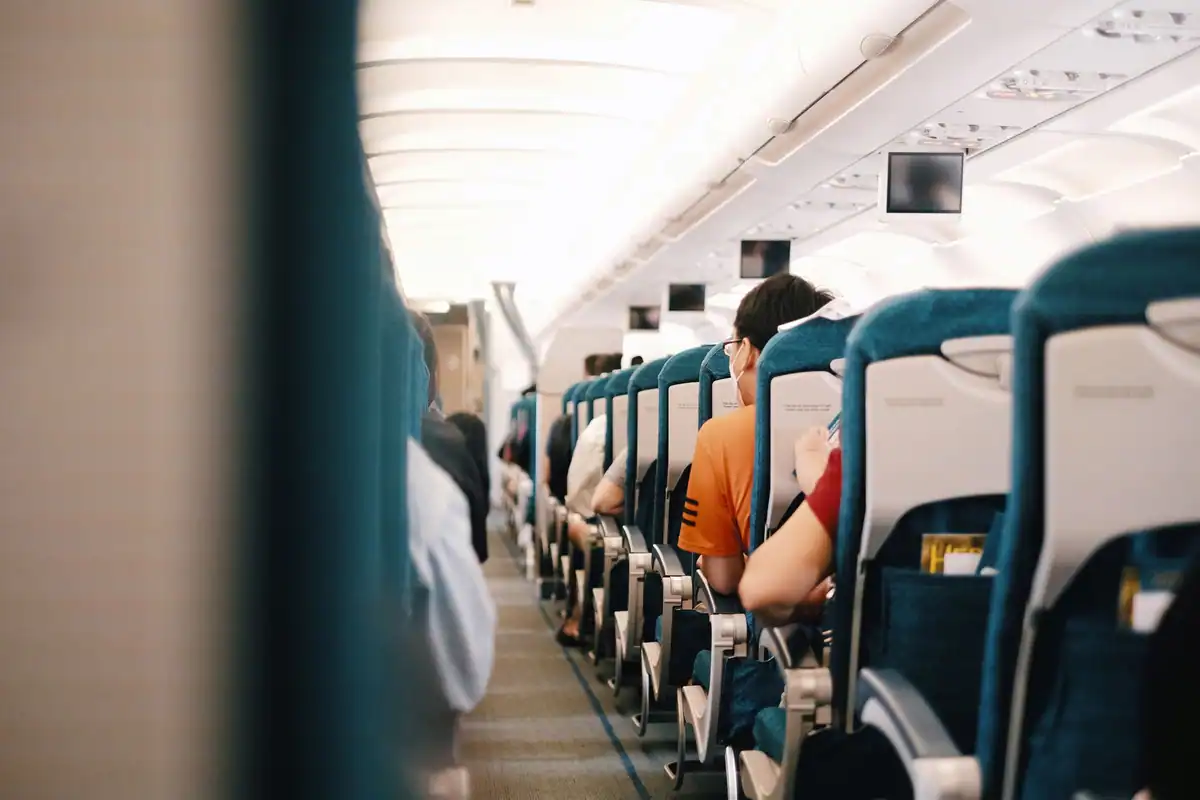 Pasageri așezați pe scaune în cabina avionului în timpul zborului