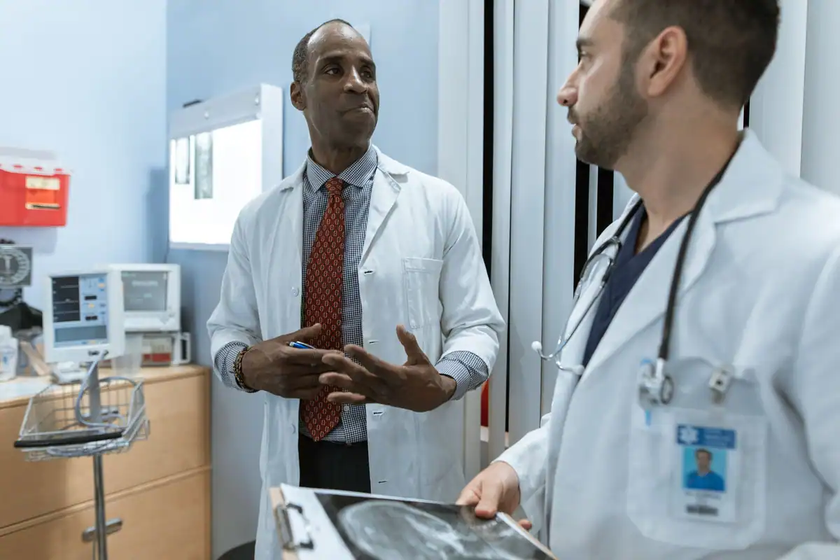 Doi medici în halate albe care discută o radiografie în cabinet