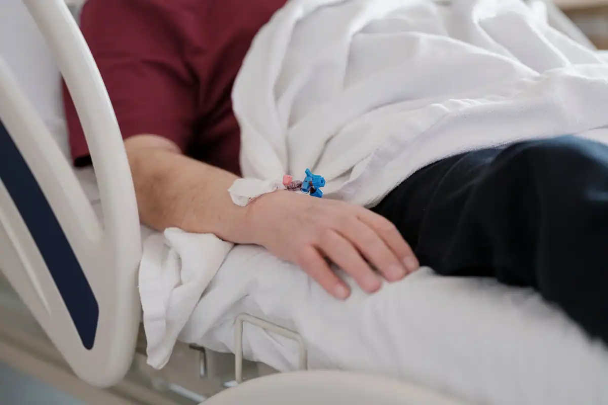 Mâna unui pacient cu perfuzie, întins pe patul de spital după procedură