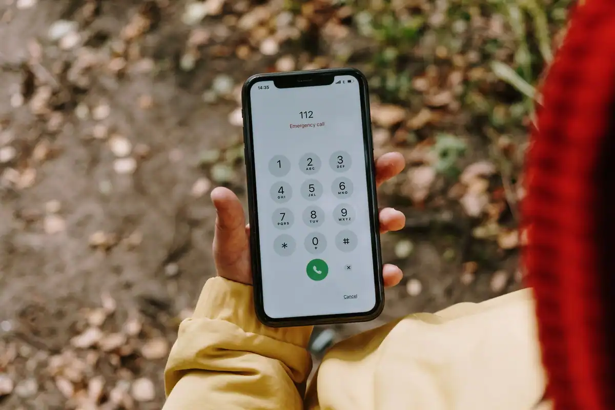 Telefon mobil care afișează numărul de urgență 112, ținut în mână afară