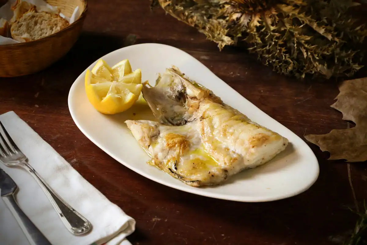Farfurie cu pește la grătar, lămâie și pâine, preparat specific dietei mediteraneene