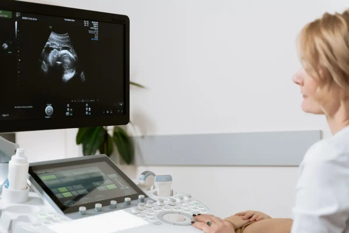 Femeie la o examinare ecografică făcută de un cadru medical