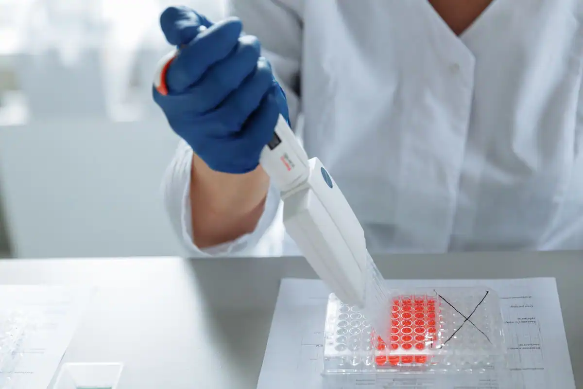 Cercetător care lucrează cu o pipetă în laborator pentru o analiză genetică