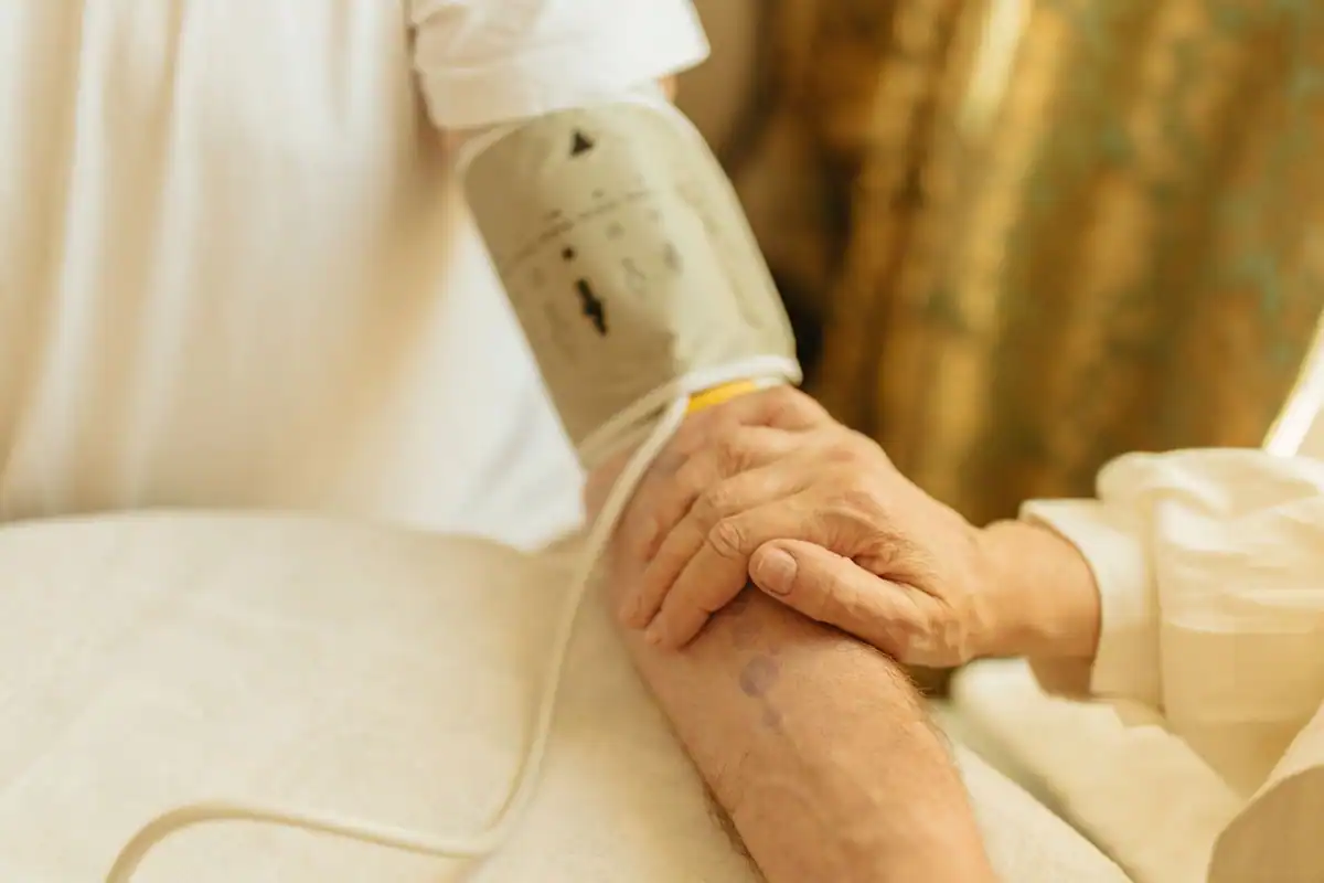 Măsurarea tensiunii arteriale pe brațul unui adult vârstnic, în casă
