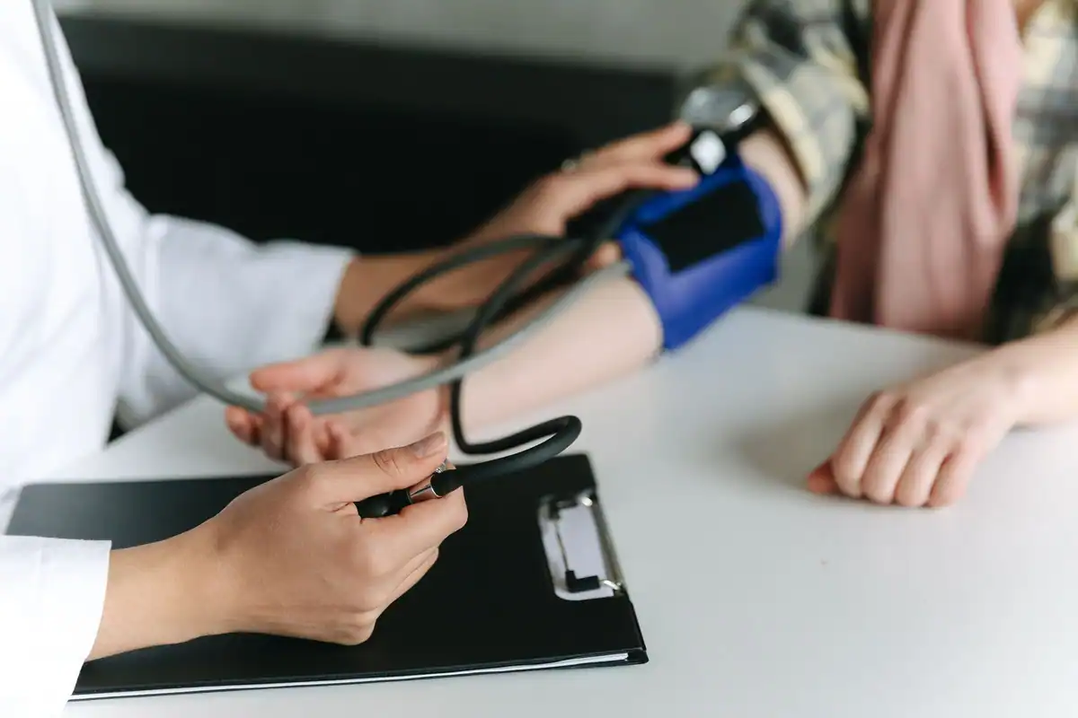 Cadru medical care măsoară tensiunea unui pacient în cabinet, unde valorile pot ieși mai mari