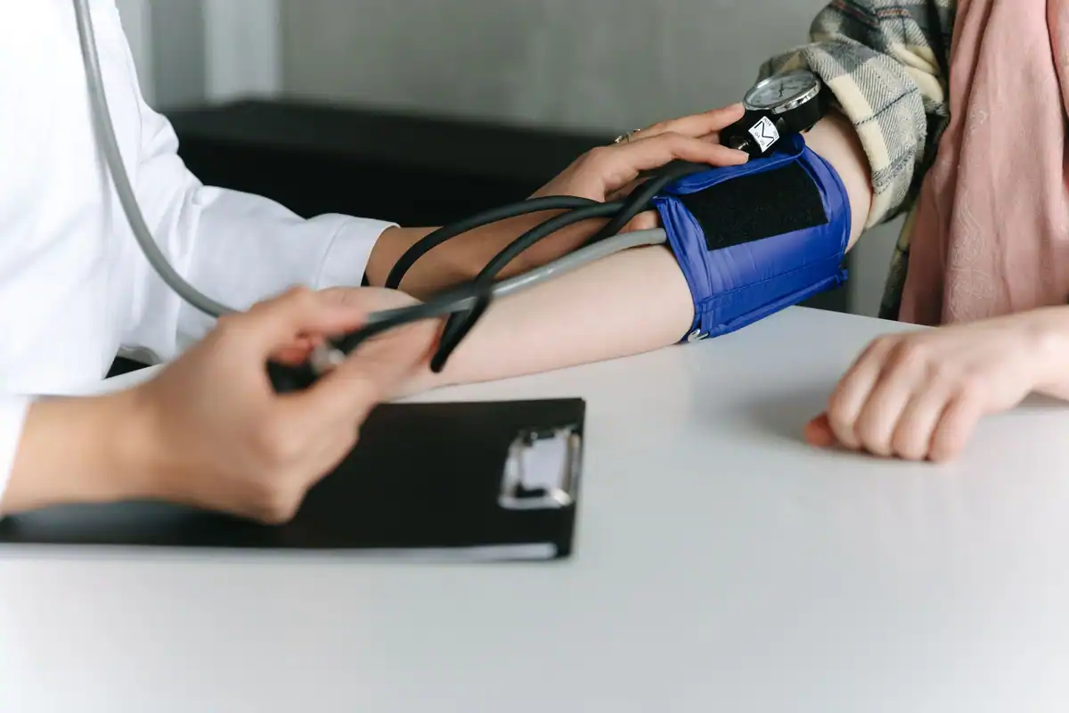 Cadru medical care măsoară tensiunea unui pacient cu tensiometrul în cabinet