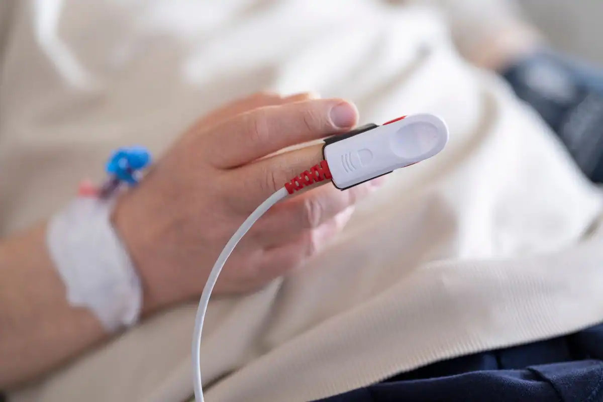 Deget de pacient cu pulsoximetru care măsoară oxigenul din sânge în spital
